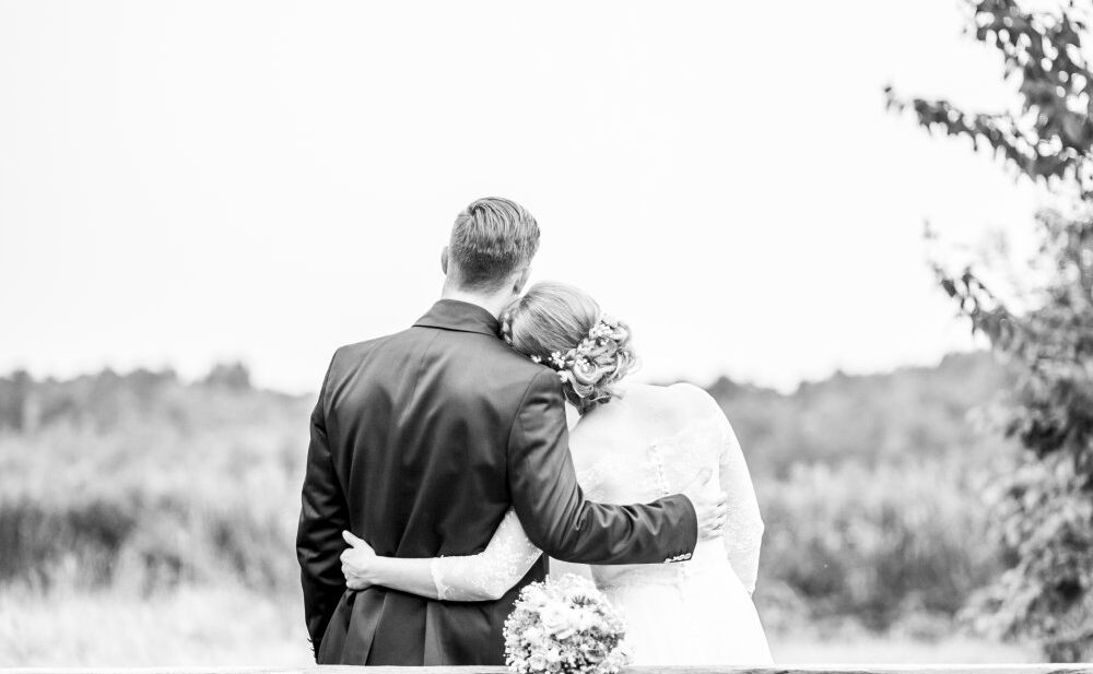 Hochzeitspaar mit Blick auf See im Garten des Seehauses