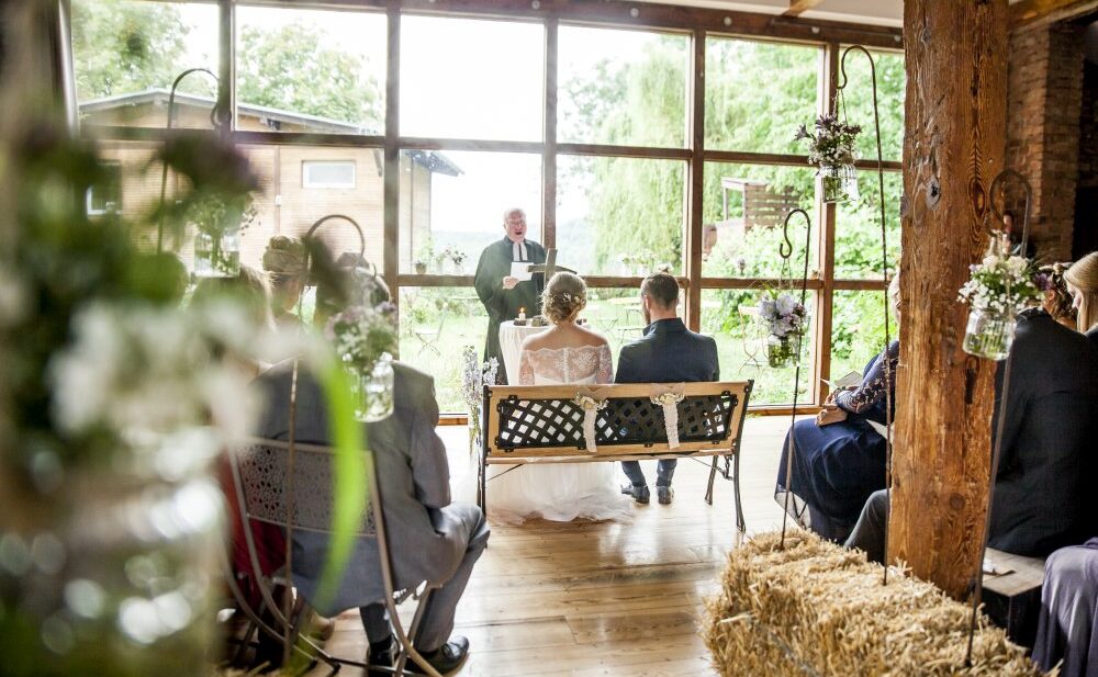 Hochzeitspaar während der Trauung in der Scheune mit Blick auf See